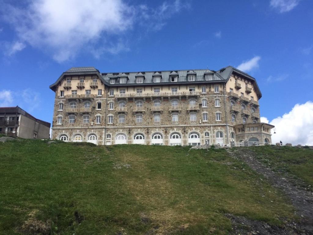 un grand bâtiment au sommet d'une colline herbeuse dans l'établissement L'esprit chalet by SODA, à Luchon