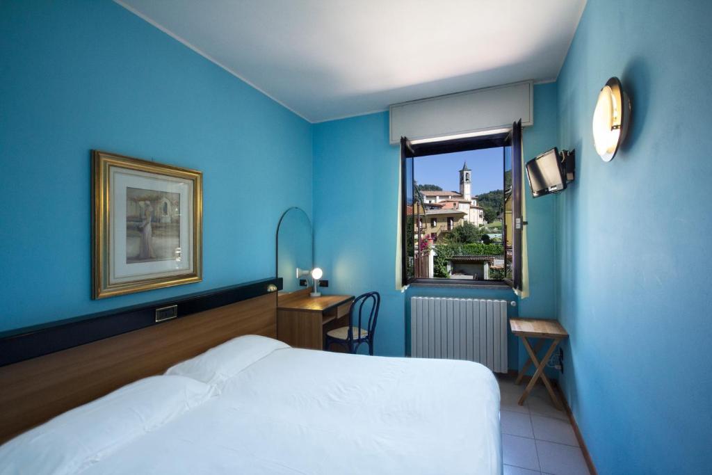 Cette chambre bleue comprend un lit et une fenêtre. dans l'établissement Albergo Sala, à Valbrona