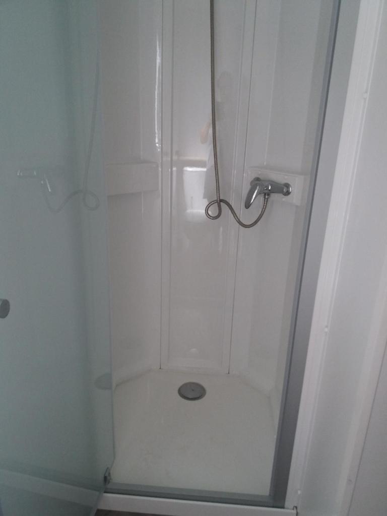 une douche avec une porte vitrée dans une salle de bain dans l'établissement Mobil home 3 chambres, à Canet