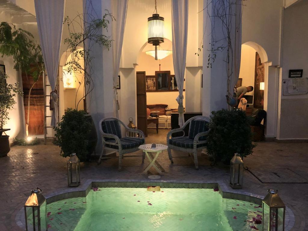 - un salon avec une piscine au milieu d'un bâtiment dans l'établissement Riad Le Coq Berbère, à Marrakech