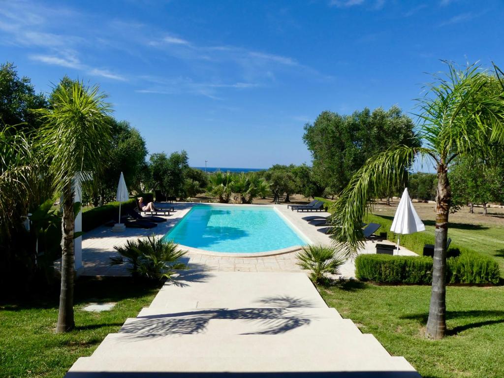 - une piscine dans un complexe avec des palmiers dans l'établissement Villa M, à Specchiolla