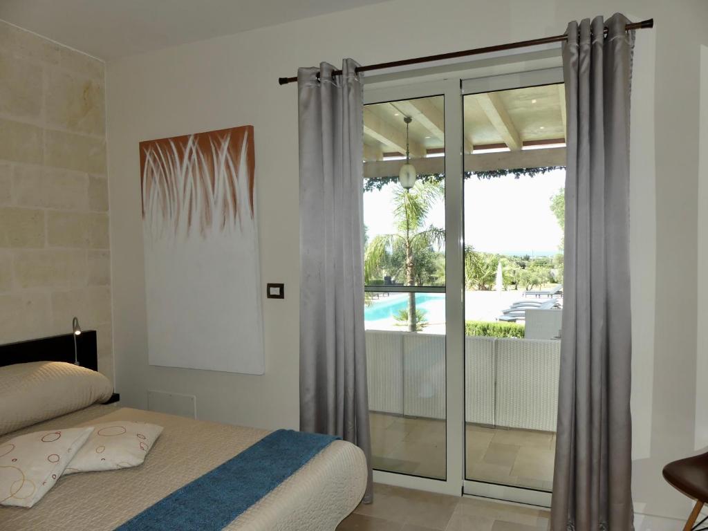 une chambre avec un lit et une vue sur une piscine dans l'établissement Villa M, à Specchiolla