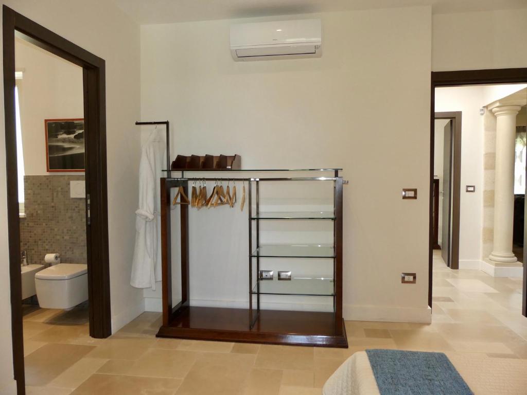 La salle de bains est pourvue de toilettes et d'une étagère en verre. dans l'établissement Villa M, à Specchiolla