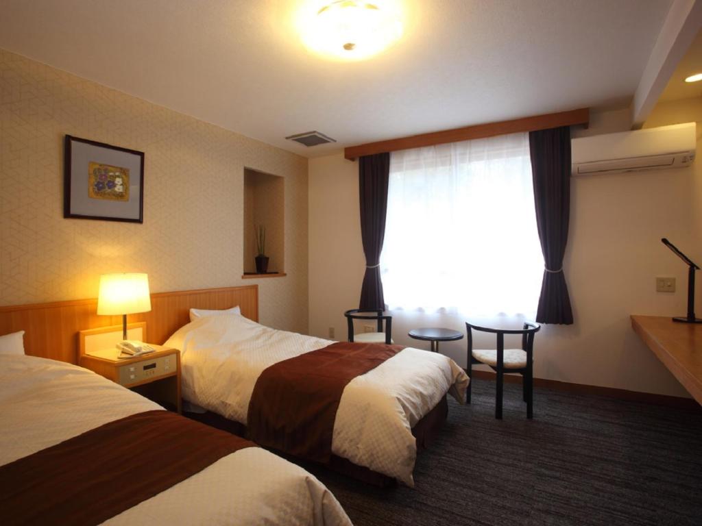 une chambre d'hôtel avec deux lits et une fenêtre dans l'établissement Kagamigaike Hekizantei, à Nihommatsu