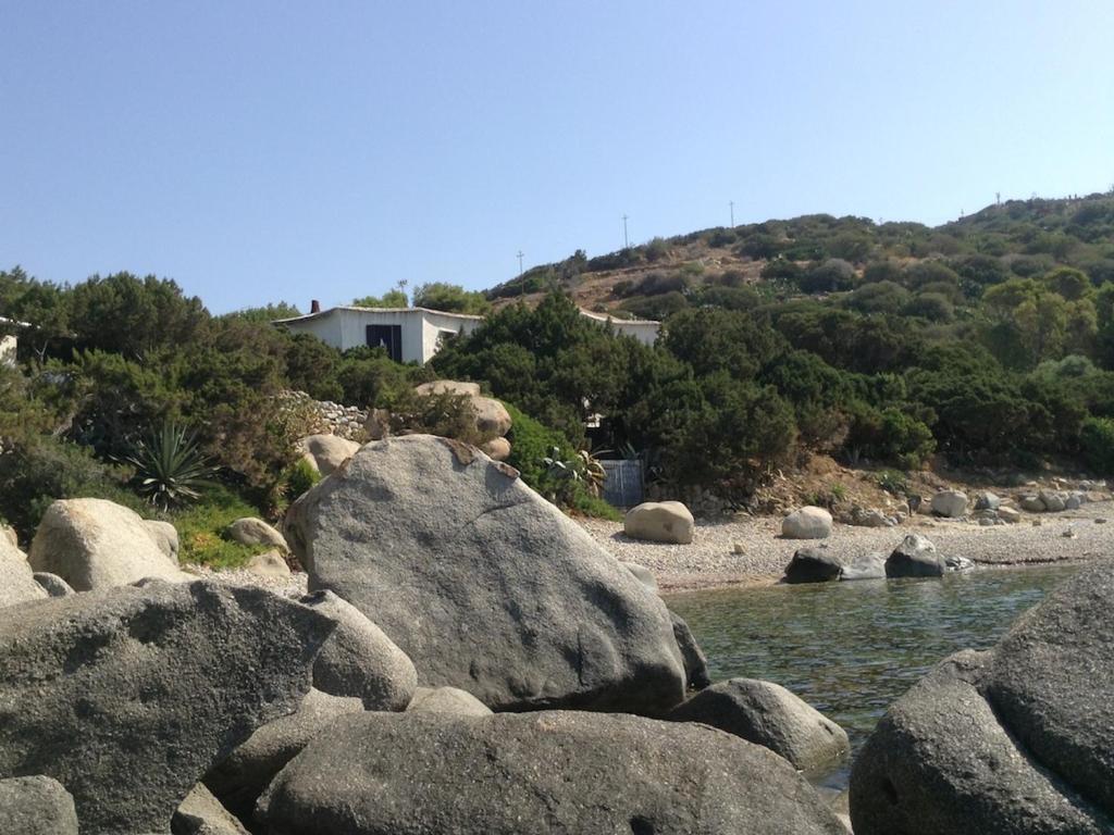 un groupe de rochers dans l'eau avec une maison dans l'établissement Sa Maluni, à Marongiu