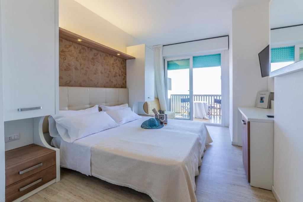 une chambre avec un grand lit blanc et un balcon dans l'établissement Eurhotel, à Rimini