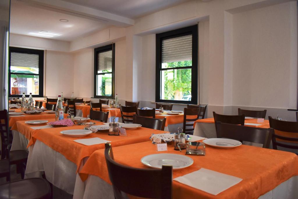 une salle à manger avec tables, chaises et fenêtres dans l'établissement Hotel Urbinati, à Bellaria-Igea Marina