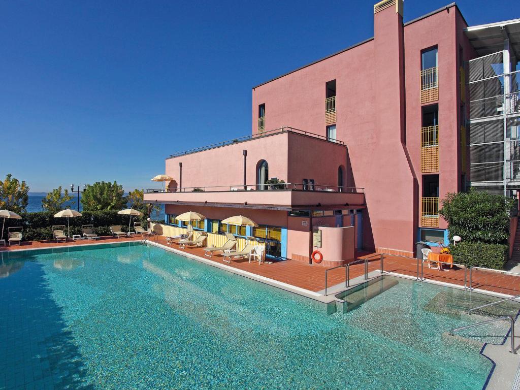 une grande piscine en face d'un bâtiment rose dans l'établissement Hotel Sportsman, à Bardolino