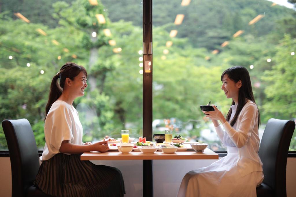 deux femmes assises à une table en train de manger dans l'établissement Hotel Hanamaki, à Hanamaki