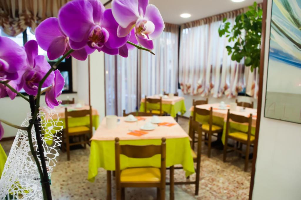 un restaurant avec des tables, des chaises et des fleurs violettes dans l'établissement Hotel Angelini, à Rimini 58 autres photos