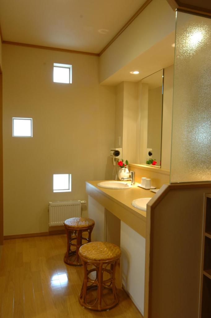 La salle de bains est pourvue d'un lavabo, d'un miroir et de tabourets. dans l'établissement Karurusu Onsen Yumoto Orofuresou, à Noboribetsu