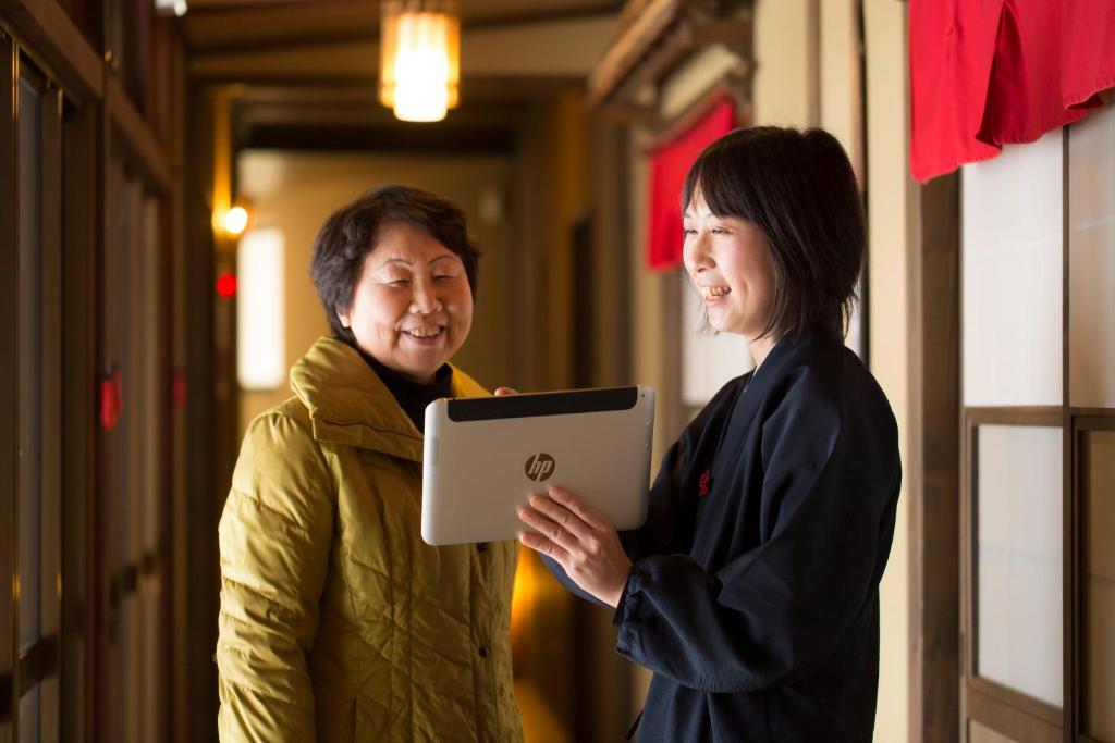 une femme debout à côté d'un homme tenant une tablette dans l'établissement Super Hydrogen Rich Spa Yado Kanzan, à Minakami