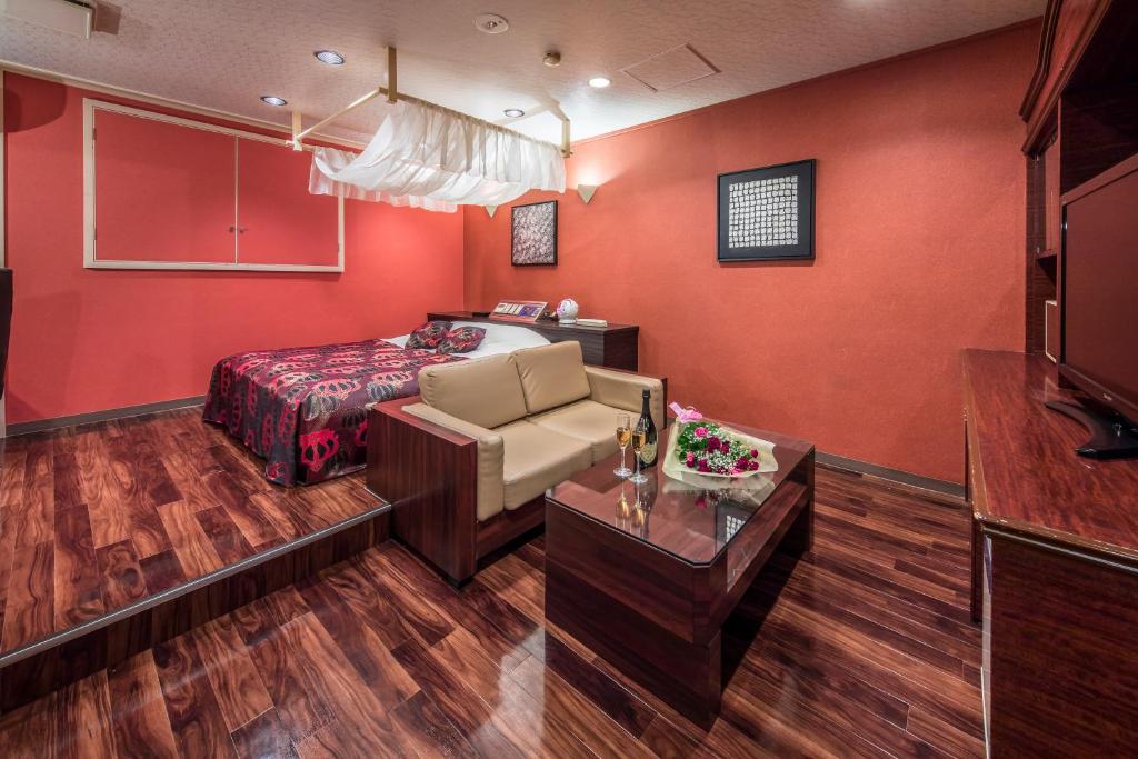 une chambre rouge avec un lit et un canapé dans l'établissement Restay Utsunomiya (Adult Only), à Utsunomiya