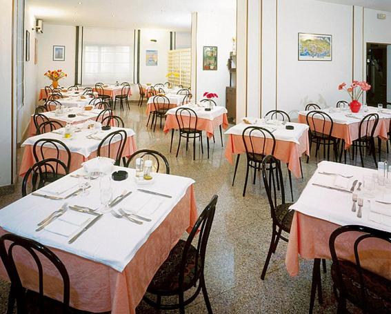 une salle à manger avec des tables et des chaises, des tables blanches et orange dans l'établissement Hotel Désirée, à San Benedetto del Tronto