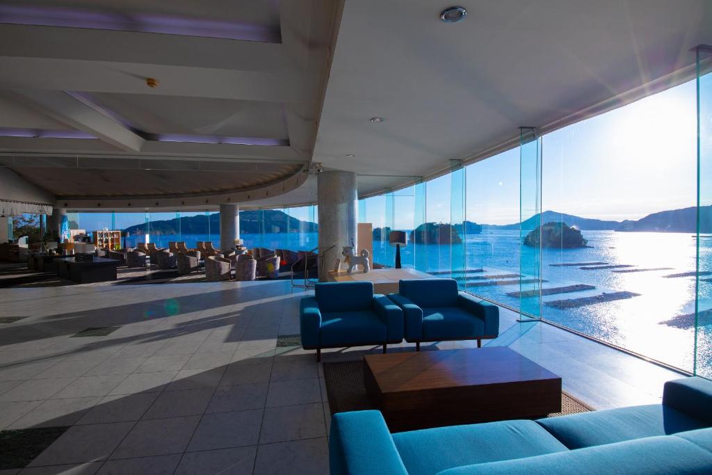 - un hall avec des chaises bleues et une vue sur l'eau dans l'établissement Toba Grand Hotel, à Toba