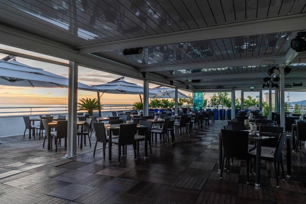 un restaurant avec tables et chaises avec vue sur l'océan dans l'établissement Hotel Abruzzo Marina, à Silvi Marina