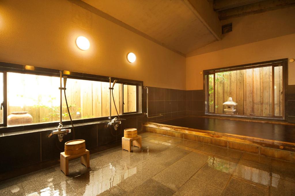 une salle de bain avec baignoire et deux fenêtres dans l'établissement 黒潮の宿 臨海荘 -Kuroshio no yado Rinkaisou-, à Katsuura