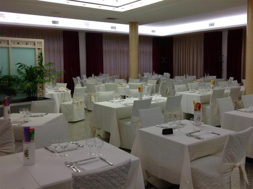 une salle de banquet avec des tables blanches et des chaises blanches dans l'établissement Hotel Ristorante Anita, à Cupra Marittima