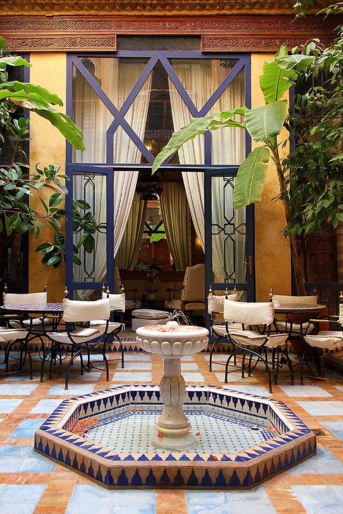 une fontaine dans une cour avec des chaises et des tables dans l'établissement Riad Soundouss, à Marrakech