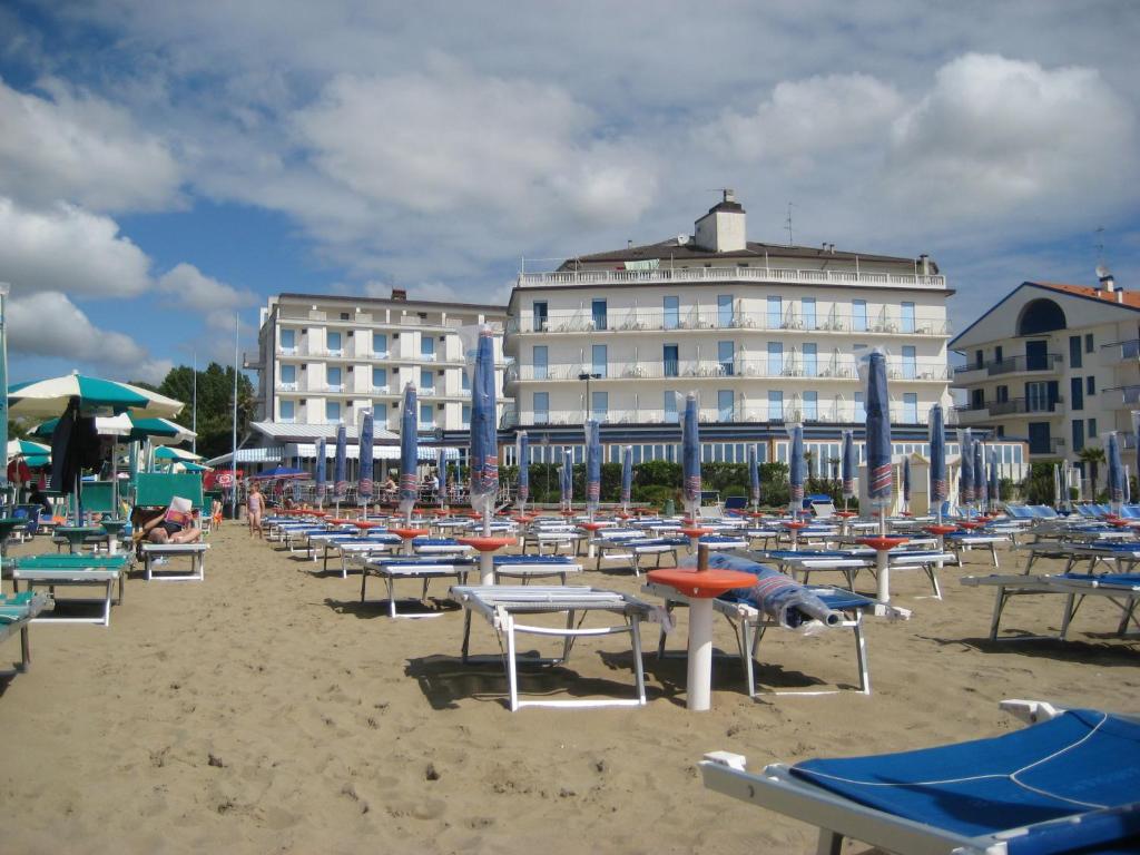 une plage avec des chaises et des parasols et un bâtiment dans l'établissement Hotel Playa e Mare Nostrum, à Caorle