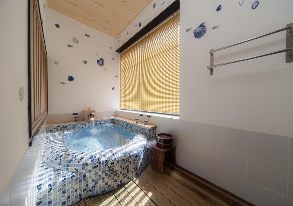 une salle de bains avec un jacuzzi et une fenêtre dans l'établissement CHAHARU Hanare Dogo Yumekura, à Matsuyama 27 autres photos