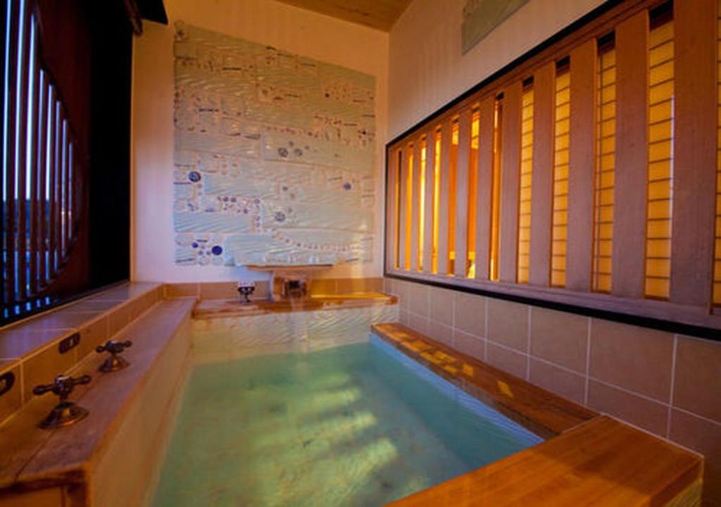 La salle de bains est pourvue d'une baignoire et d'un lavabo. dans l'établissement CHAHARU Hanare Dogo Yumekura, à Matsuyama