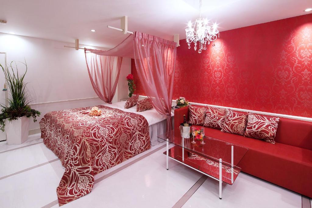 une chambre rouge avec un lit et un canapé dans l'établissement Restay Okayama (Adult Only), à Okayama