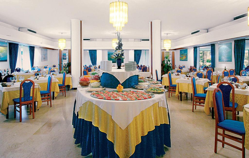 une salle à manger avec des tables et des chaises avec de la nourriture dans l'établissement Hotel Meridianus, à Lignano Sabbiadoro