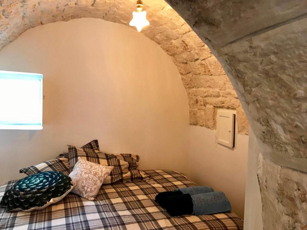 un lit dans une chambre avec un mur en pierre dans l'établissement Trulli Storie di Puglia - Private Pool, à Polignano a Mare
