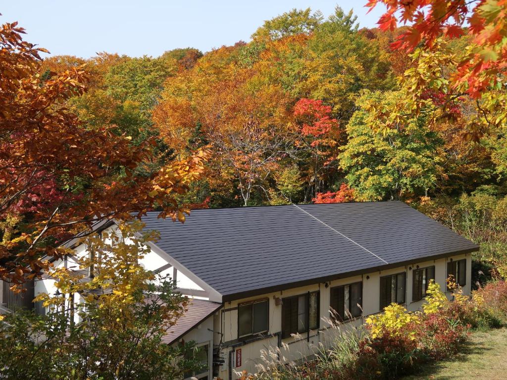 une maison avec un toit noir devant les arbres dans l'établissement Yachi Onsen, à Towada 37 autres photos