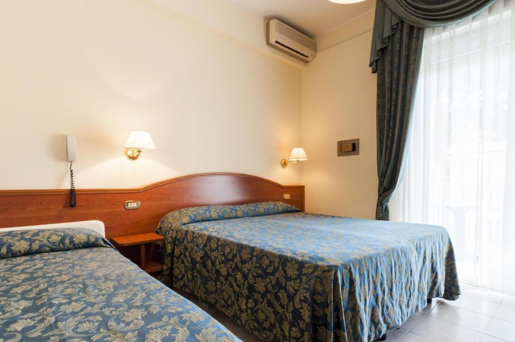 une chambre d'hôtel avec deux lits et une fenêtre dans l'établissement Hotel Donatella Pinarella, à Cervia