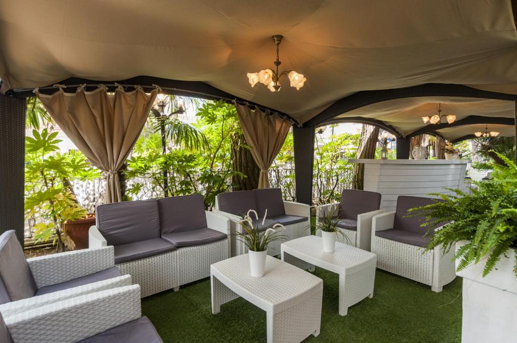 un groupe de chaises et de tables sur une terrasse dans l'établissement Hotel Donatella Pinarella, à Cervia
