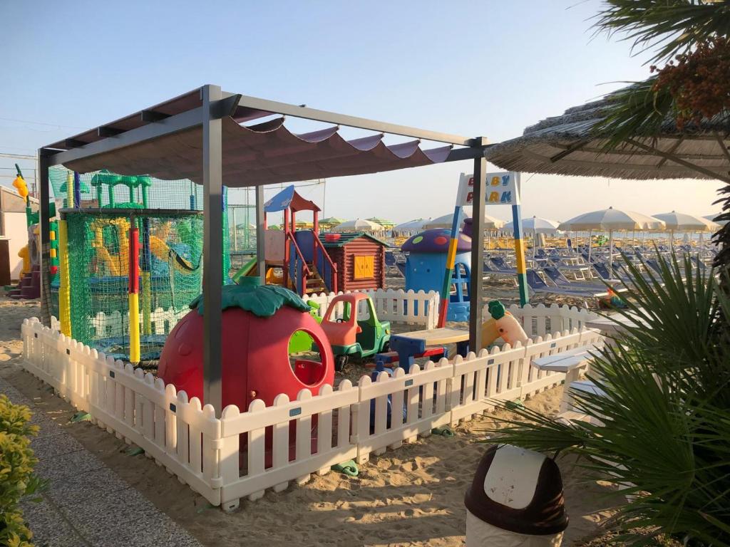 une aire de jeux pour enfants avec une clôture et un parc de jeux dans l'établissement Hotel Donatella Pinarella, à Cervia
