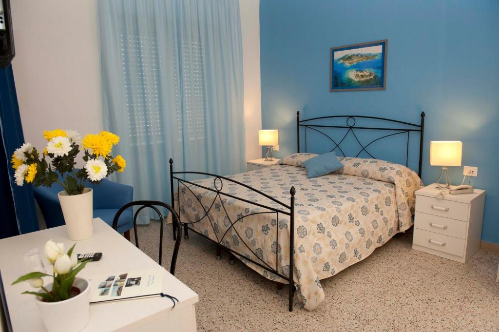 - une chambre avec un lit et 2 tables avec des fleurs dans l'établissement Hotel Venere, à Ascea