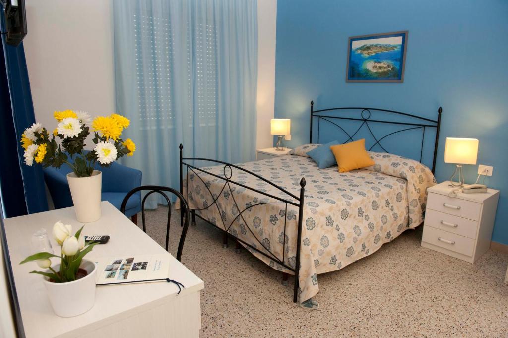 - une chambre avec un lit et 2 tables avec des fleurs dans l'établissement Hotel Venere, à Ascea