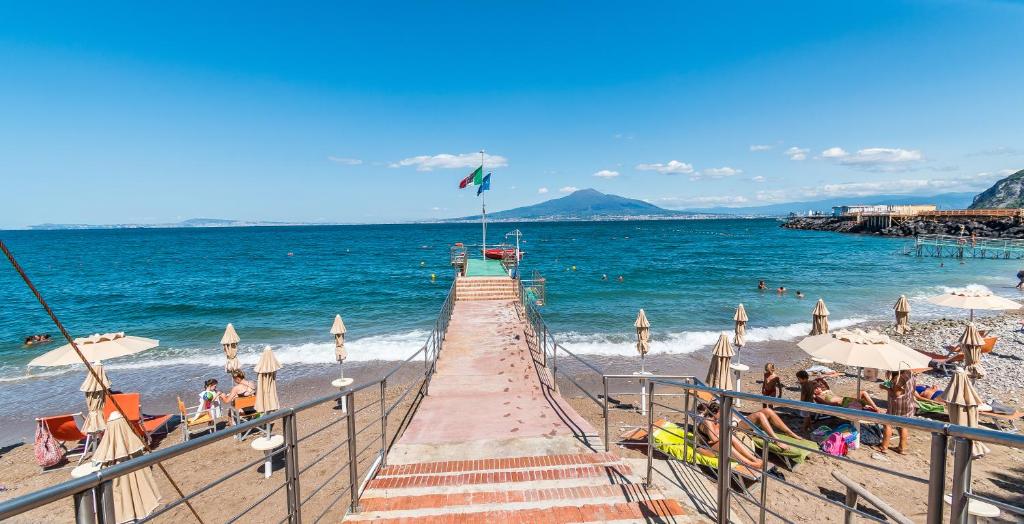 une plage avec des gens sur le sable et l'océan dans l'établissement Hotel Le Axidie, à Vico Equense