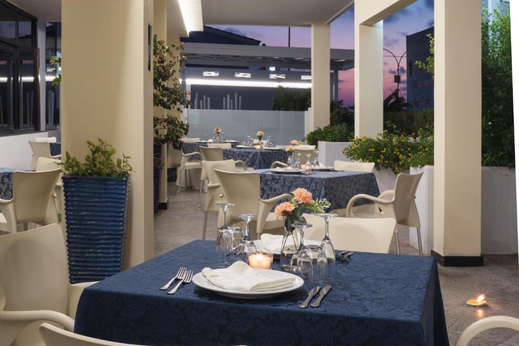 un restaurant avec des tables bleues et des chaises blanches dans l'établissement Hotel Luna Lido, à Torre San Giovanni