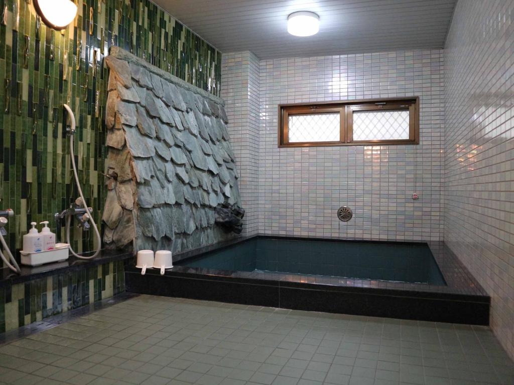 une salle de bain avec baignoire et douche dans l'établissement Kimatsu Ryokan, à Hiroshima