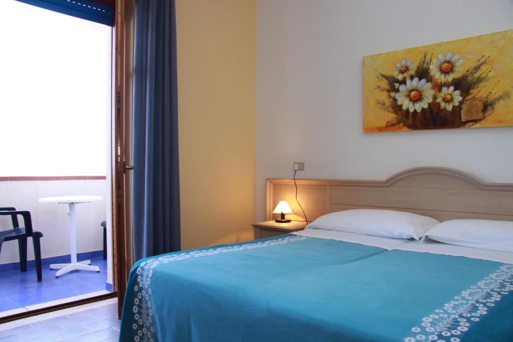 une chambre avec un lit avec une couverture bleue et une fenêtre dans l'établissement Hotel Il Gabbiano Beach, à Terme Vigliatore