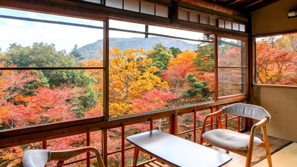2 chaises et une table devant une grande fenêtre dans l'établissement Gora Kansuiro, à Hakone