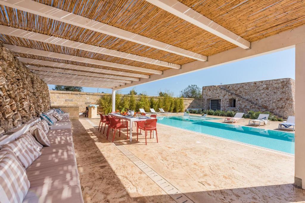 un patio extérieur avec une table et des chaises ainsi qu'une piscine dans l'établissement Villa Arja, à Corsano