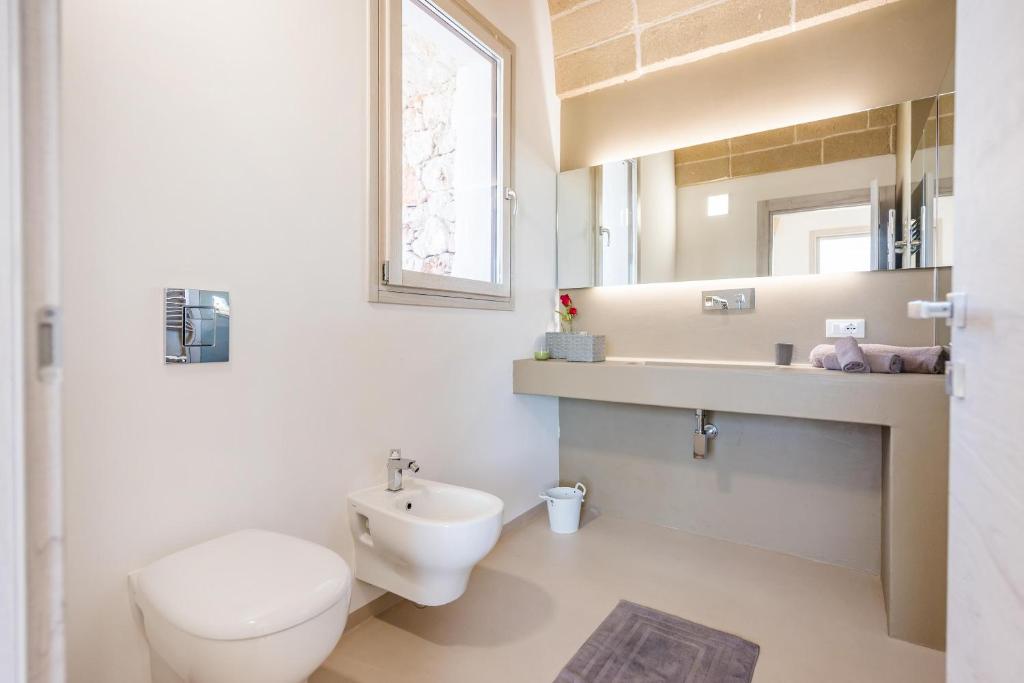 une salle de bain avec toilettes, lavabo et miroir dans l'établissement Villa Arja, à Corsano 31 autres photos