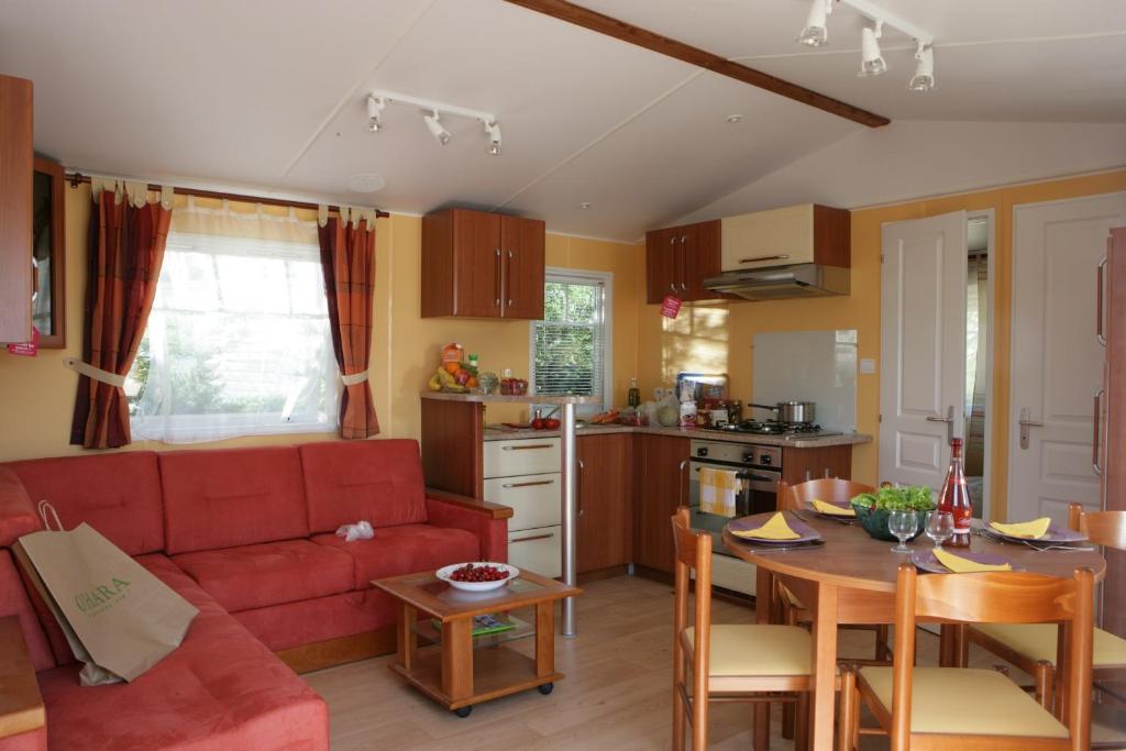 un salon avec un canapé rouge et une table dans l'établissement Camping Officiel Siblu La Carabasse, à Vias