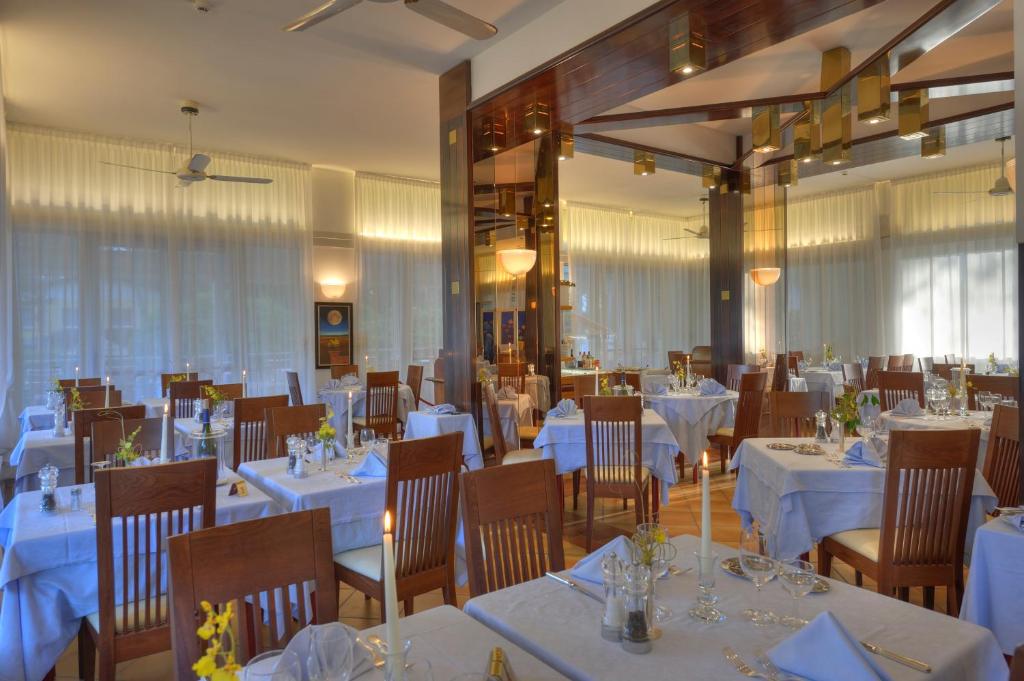 une salle à manger avec des tables et des chaises blanches dans l'établissement Hotel Arizona, à Lignano Sabbiadoro