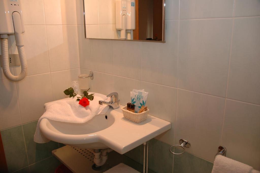 une salle de bain avec un lavabo blanc et un miroir dans l'établissement Hotel Elvia, à Lignano Sabbiadoro 34 autres photos