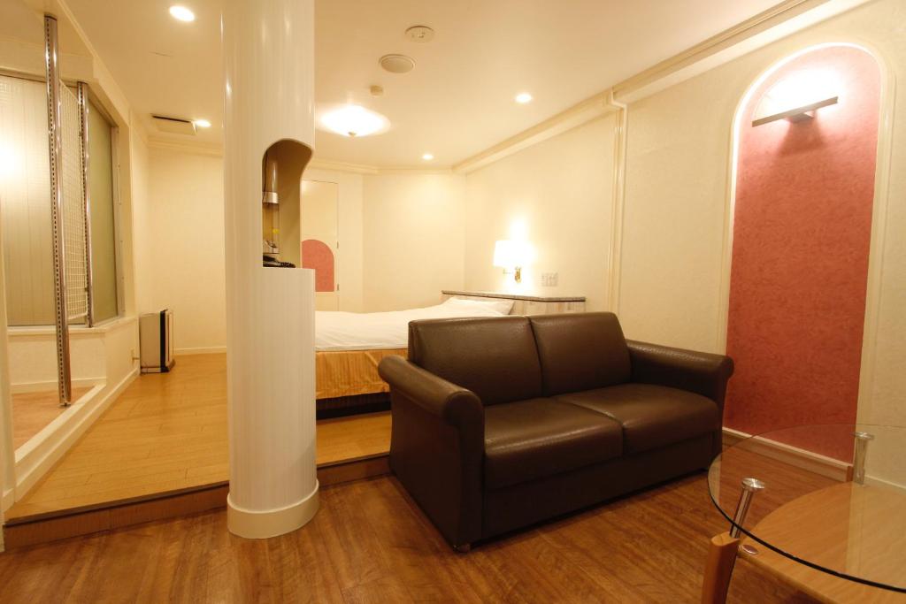 un salon avec un canapé et un lit dans l'établissement Hotel Mio (Adult Only), à Kariya