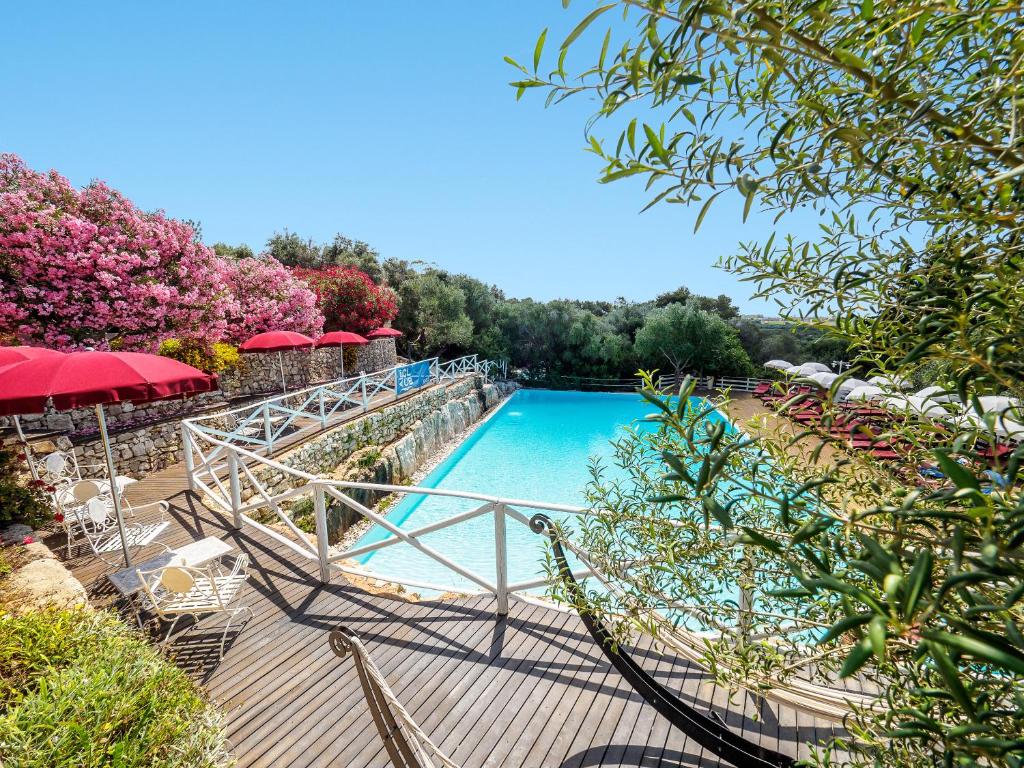 - une piscine avec des chaises et des parasols sur une terrasse en bois dans l'établissement Antica Masseria Rottacapozza, à Torre San Giovanni