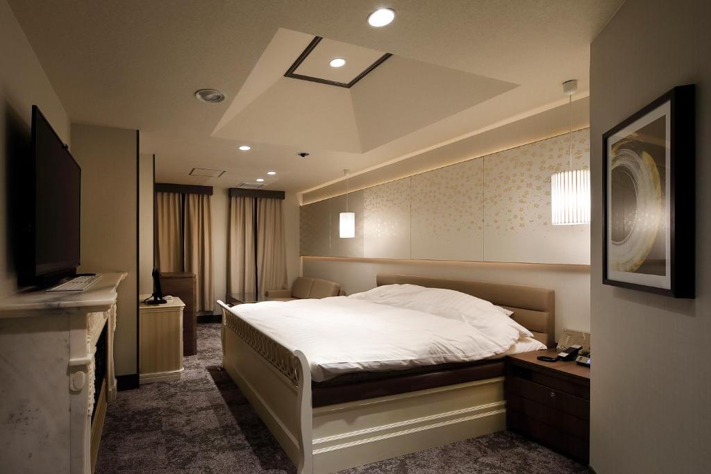 une chambre avec un lit blanc et une télévision dans l'établissement Hotel ValentineTogo (Adult Only), à Togo