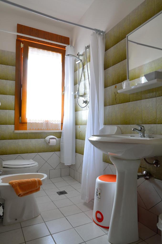 une salle de bain avec un lavabo et des toilettes et une fenêtre dans l'établissement Aurora Residence, à Lido Adriano 49 autres photos