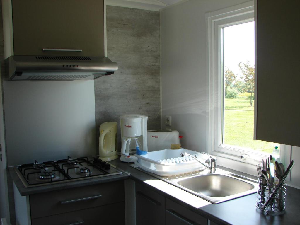 une cuisine avec un évier, une cuisinière et une fenêtre dans l'établissement Camping Moulin de Collonge, à Saint-Boil